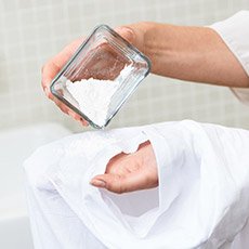 Frau schüttet Pulver auf ihre Haut